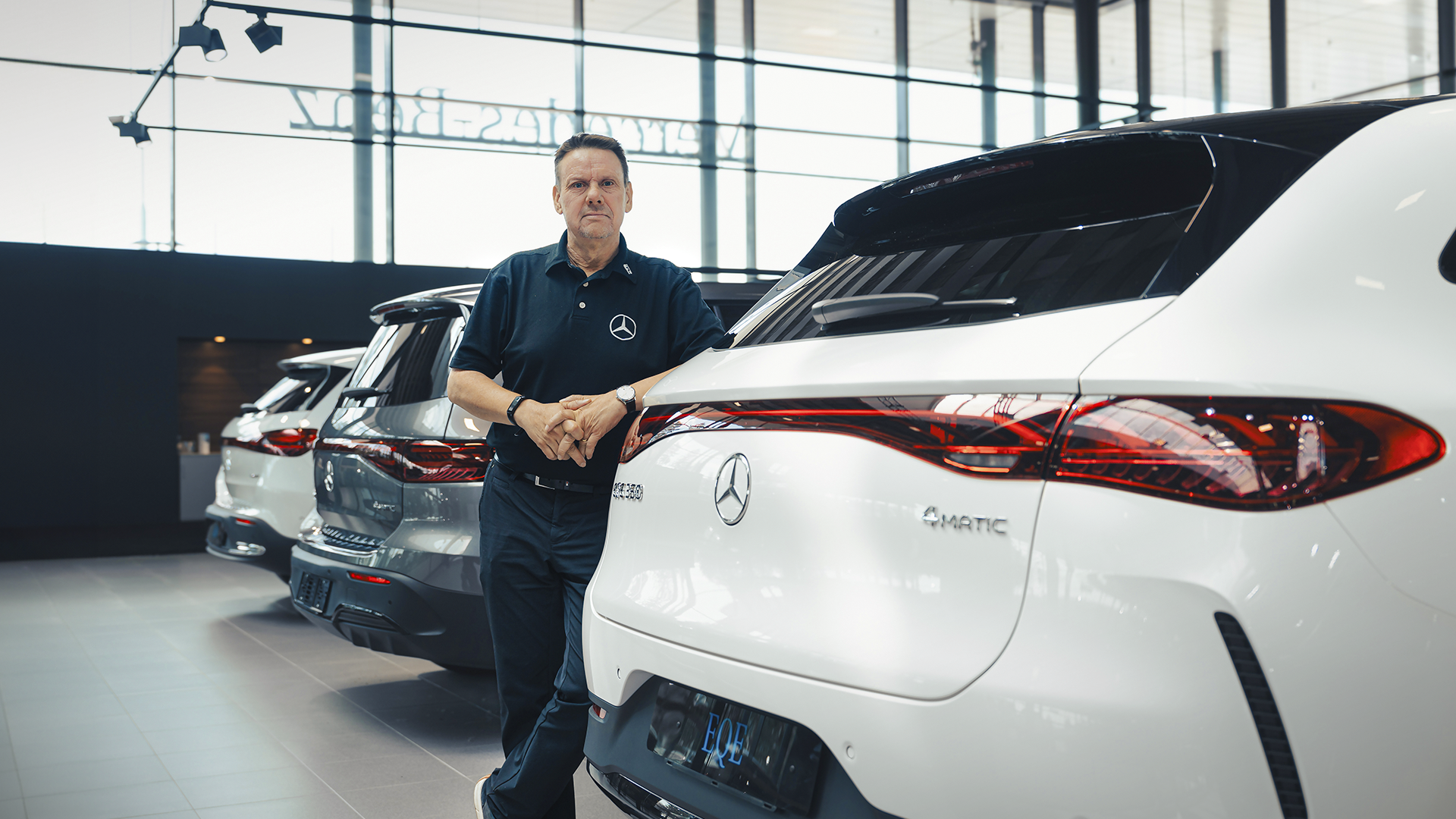 Yritysmyyntipäällikkö Jarko Penttinen nojaa autoliikkeessä valkoiseen Mercedes henkilöautoon.