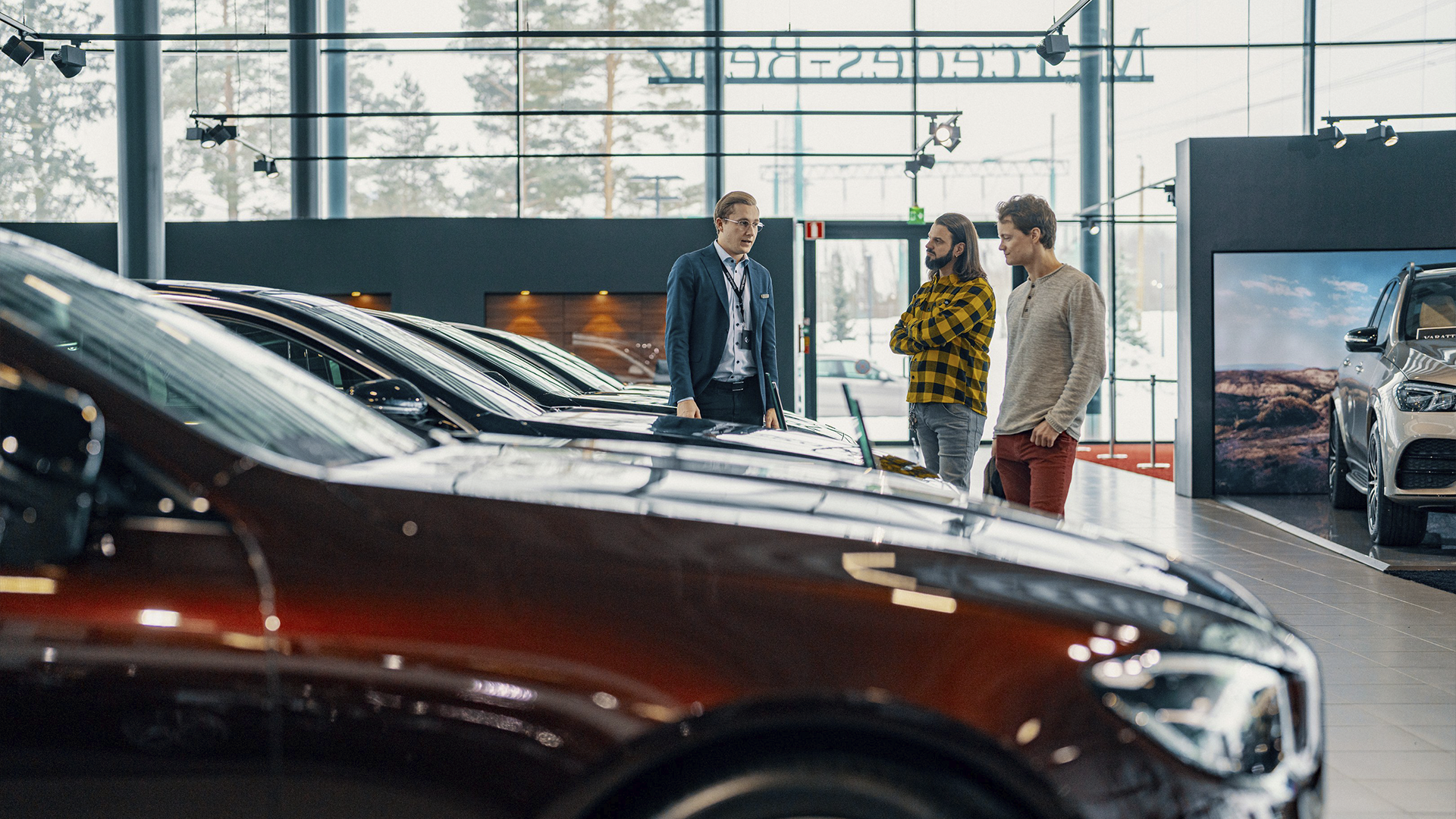 Automyyjä ja asiakkaat keskustelevat autosta liikkeessä