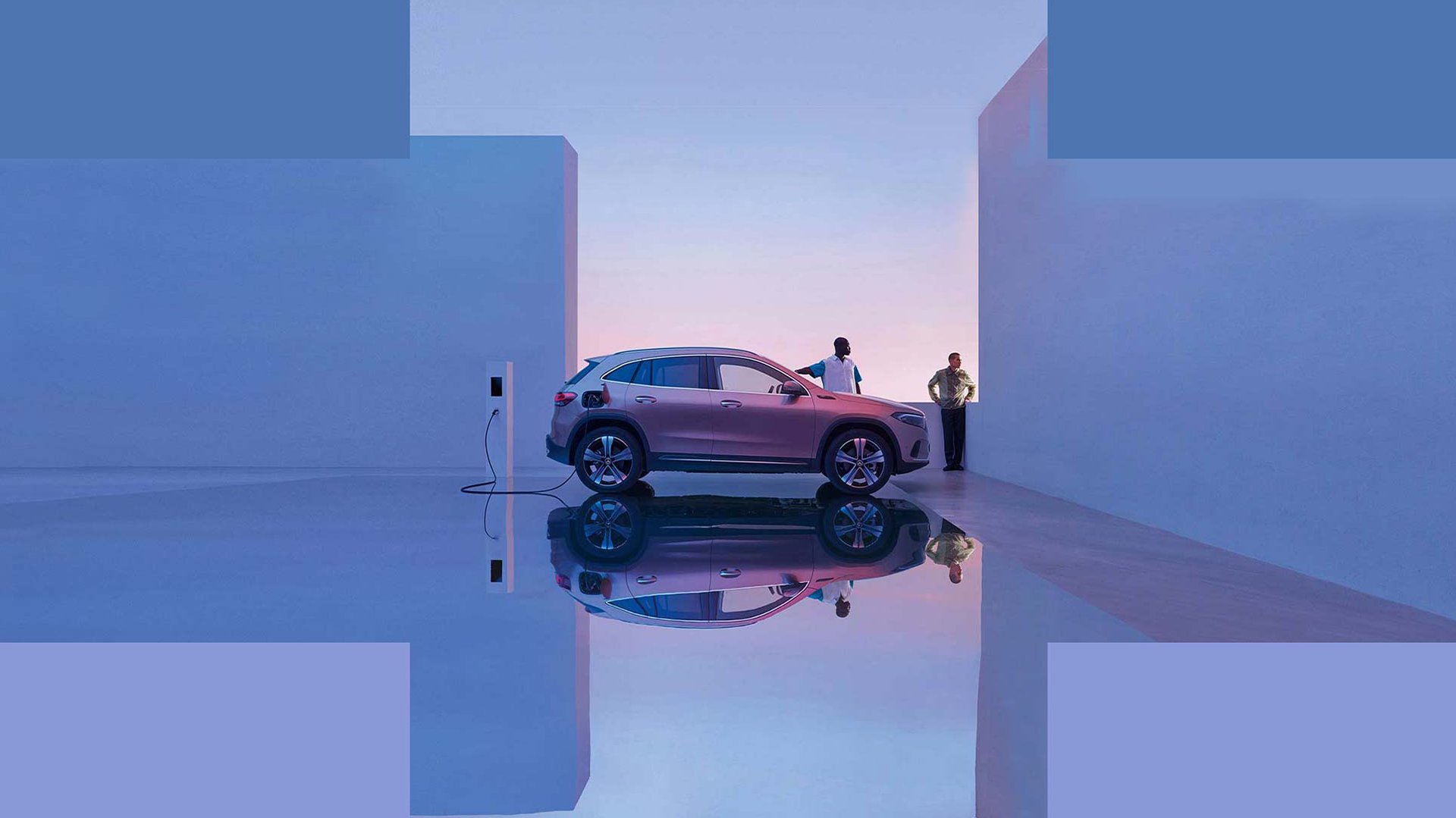 Mercedes-Benz EQA-täyssähköauto modernissa ympäristössä latauksessa. Kaksi ihmistä taustalla.