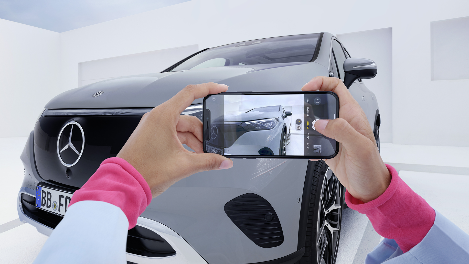 Harmaan Mercedes-maastoauton vaurioiden kuvaaminen kännykällä.