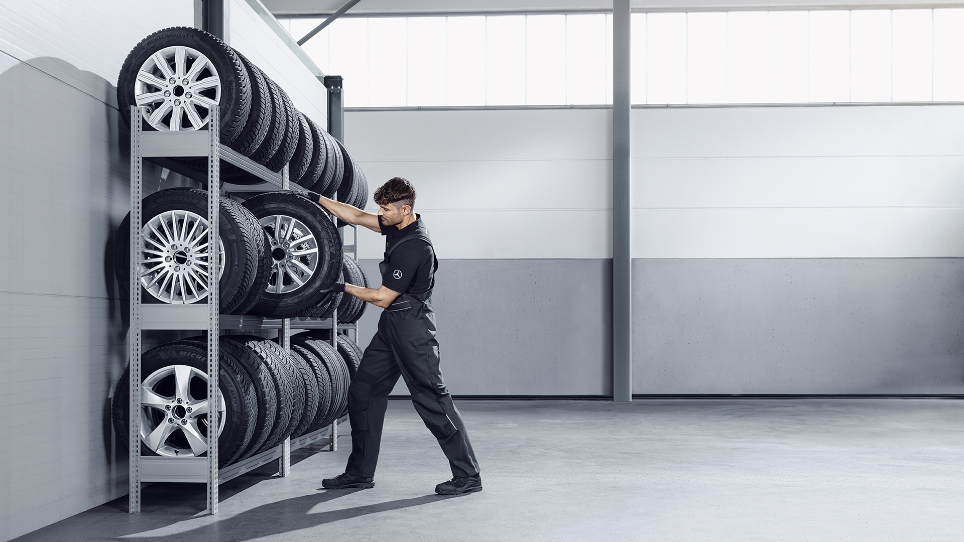 Mekaanikko asettamassa rengasta rengashyllyyn.