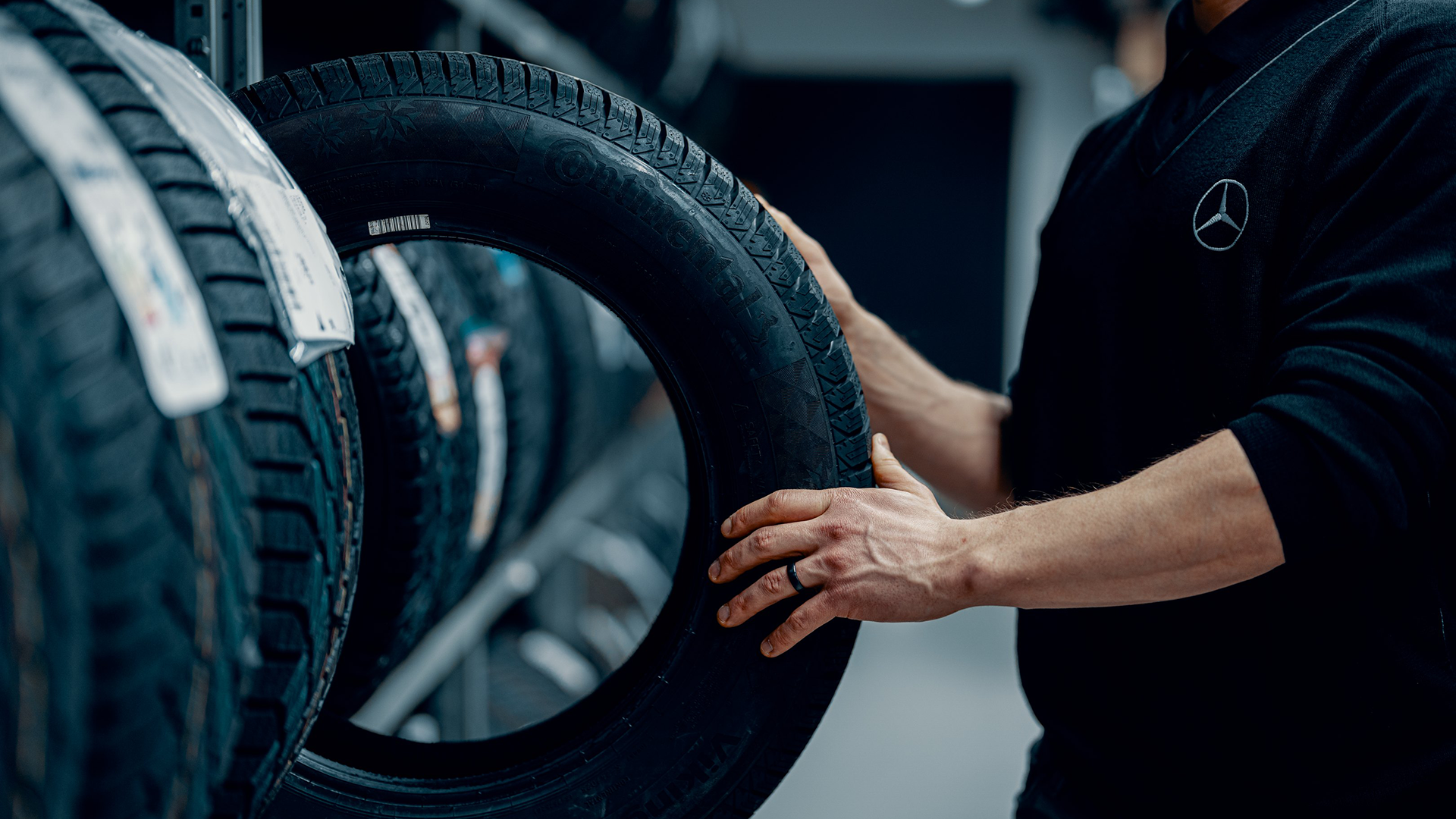 Henkilö ottamassa uutta autonrengasta rengashyllystä.