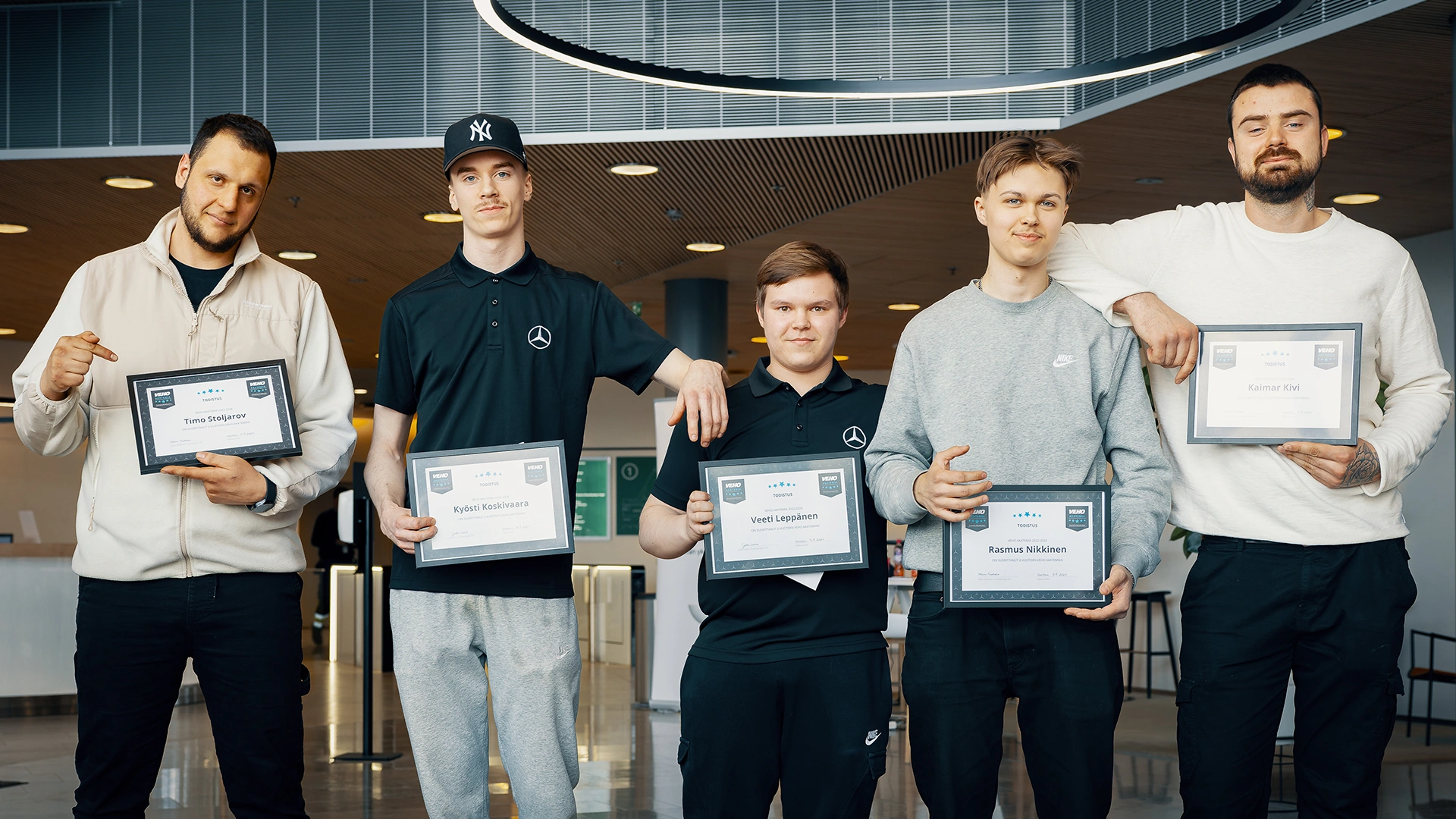 Viisi vastavalmistunutta mekaanikkoa rivissä toimiston aulassa.