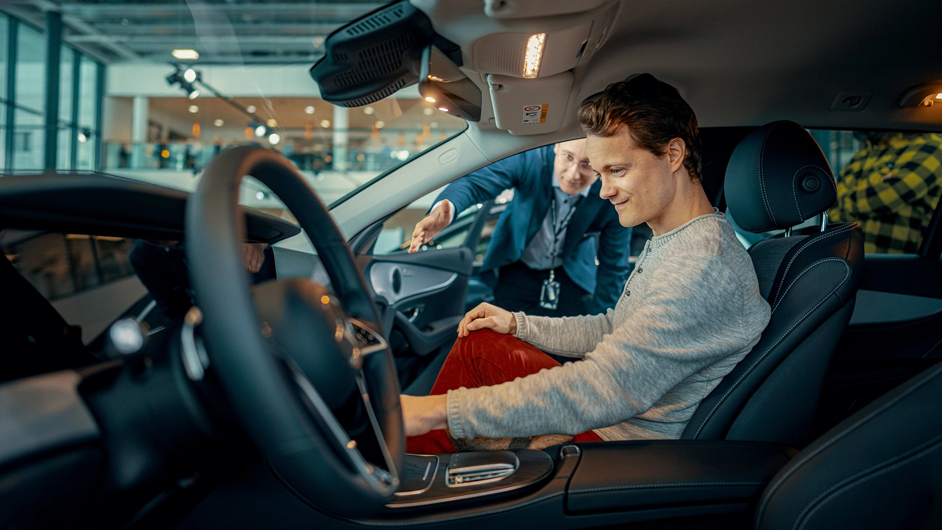 Nuori mies istuu autossa apukuljettajan paikalla ja tutkii autoa.