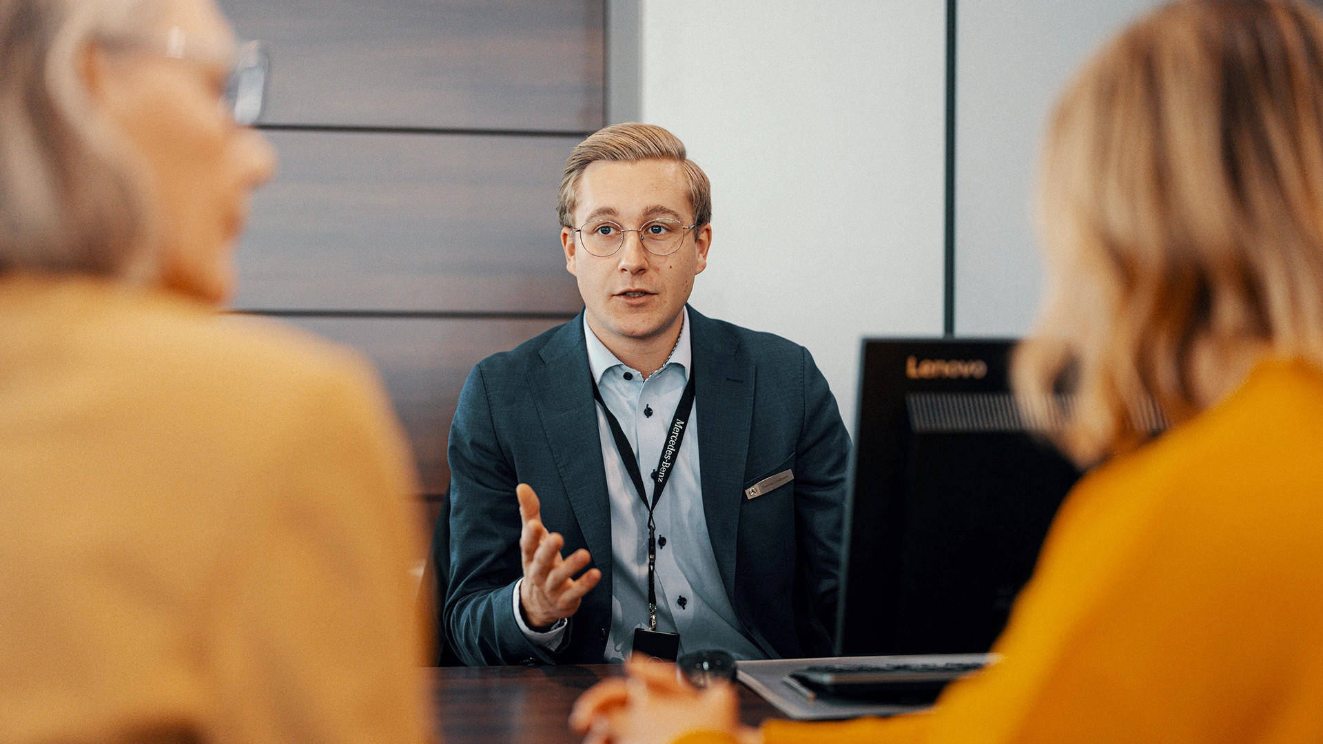 Automyyjä keskustelee työpöydän ääressä kahden asiakkaan kanssa.