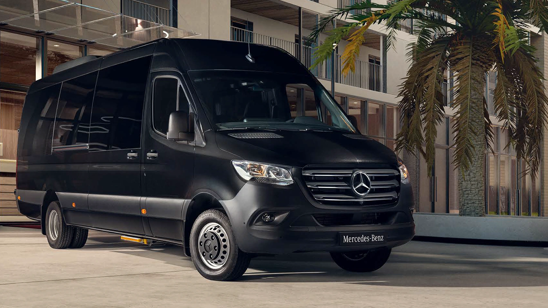 Mercedes-Benz Sprinter linja-auto tiellä rakennuksen edessä.