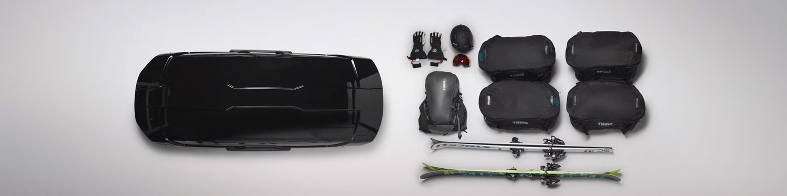 Thule Motion XT XL -suksiboksi, jonka vieressä esimerkki laskettelutarvikkeista, jotka mahtuvat laatikkoon.